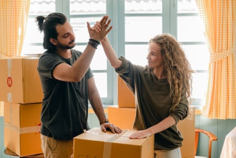 Two people are standing next to some boxes, giving high five