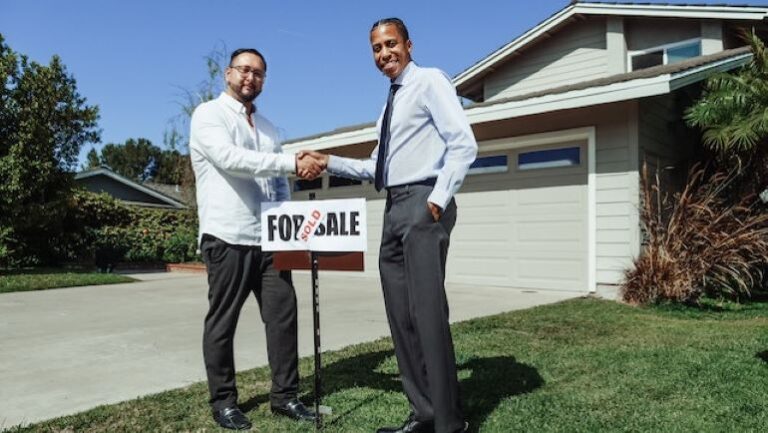 Two men are shaking hands in front of a house