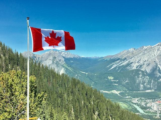 A Canadian flag with mountains in the back