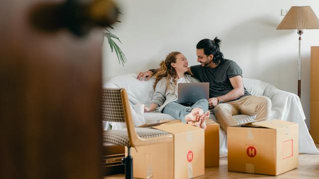 Couple sitting on a couch with a couple of moving boxes in front of them