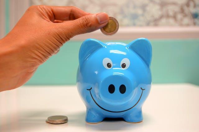 Hiring a full-service moving company is practical and cost-efficient at the same time. Alt text: Person putting a coin in a blue piggy bank