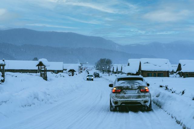 Cars driving on a snow-covered road in a winter landscape illustrate the challenges of winter travel