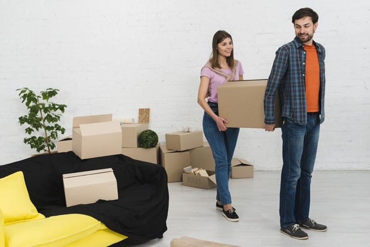 A couple carrying boxes while moving so they can deal with excess belongings before a major move